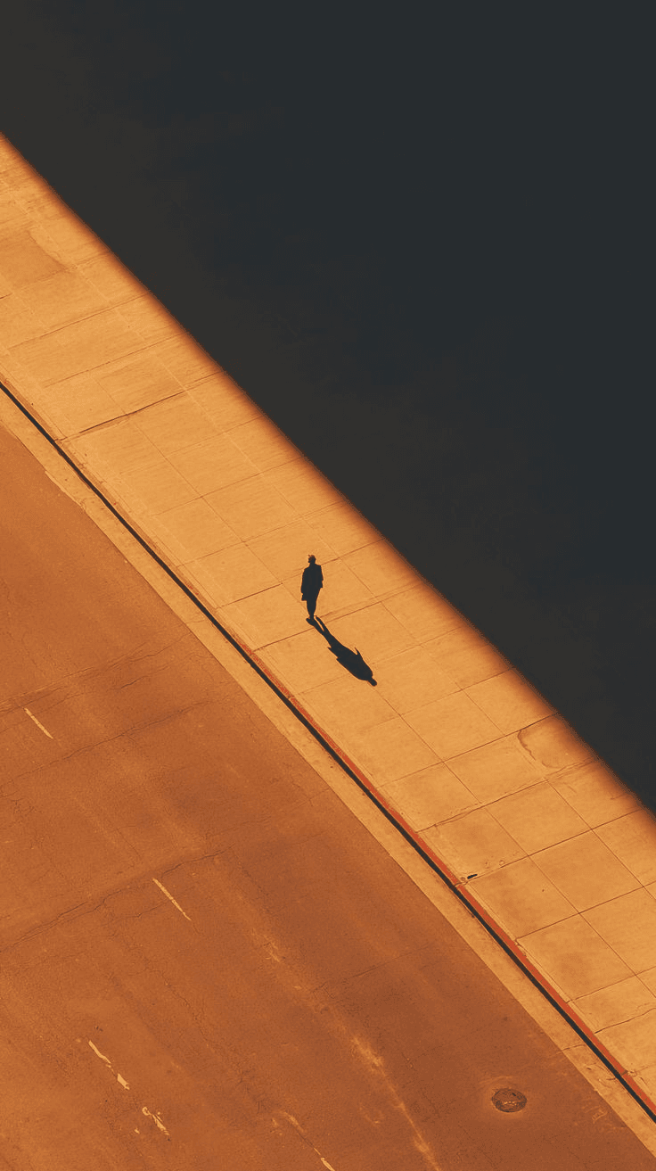 Lone figure crossing a sunlit walkway